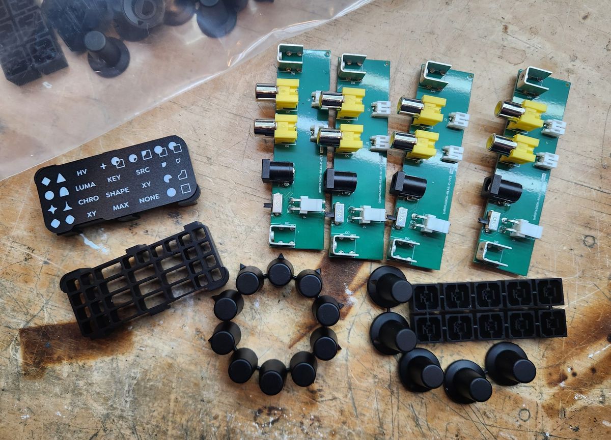 Button legend, LED grid, knobs, button caps, and four rear connector boards on a workbench